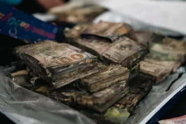 Zniszczone, brudne i wilgotne banknoty sto dolarowe ułożone w stos na folii.